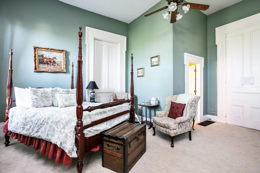 Guest room with soft green walls, four poster bed and chair at our romantic Bed and Breakfast in Kentucky