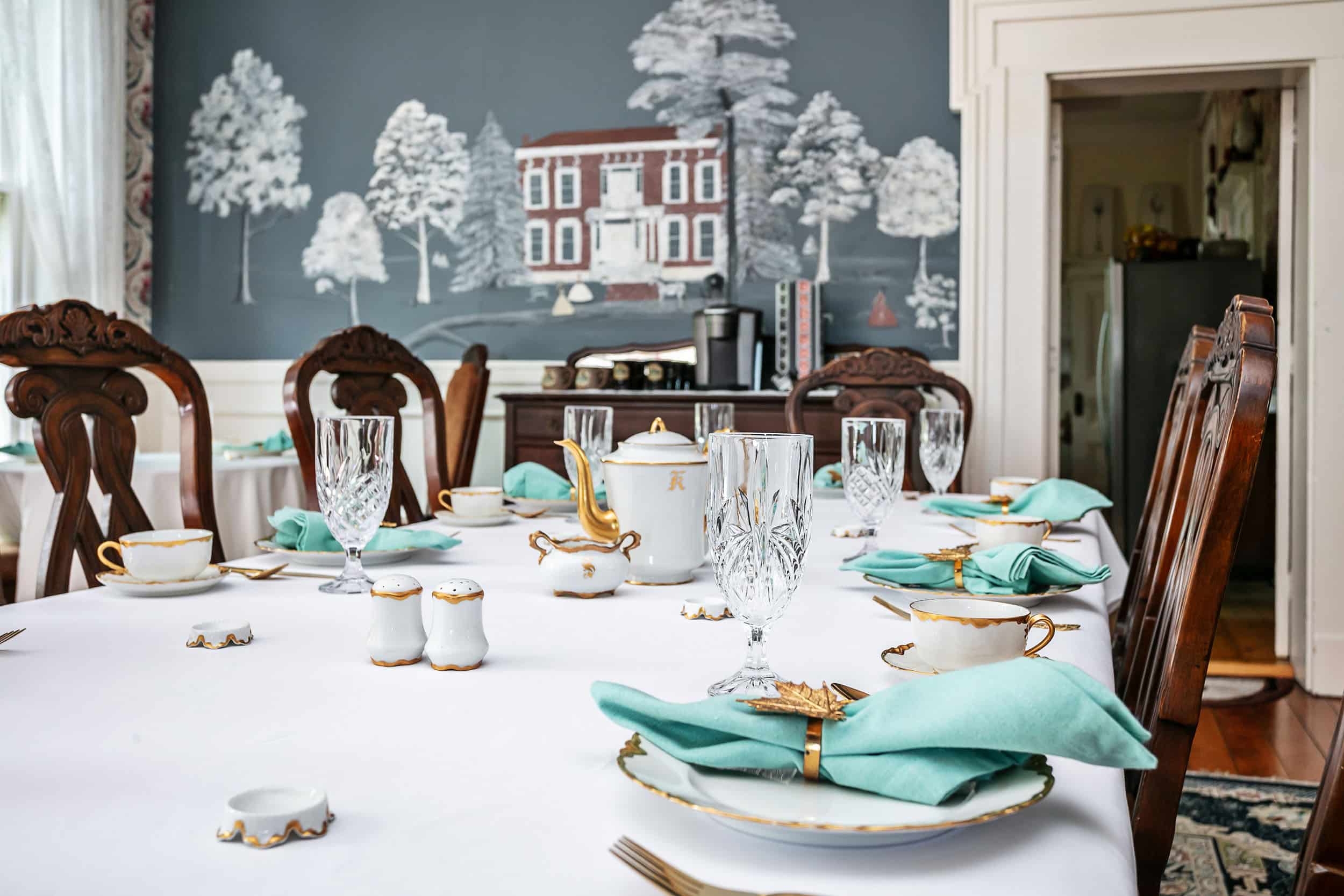 white linen table set with mural of Maple Hill Manor on the wall