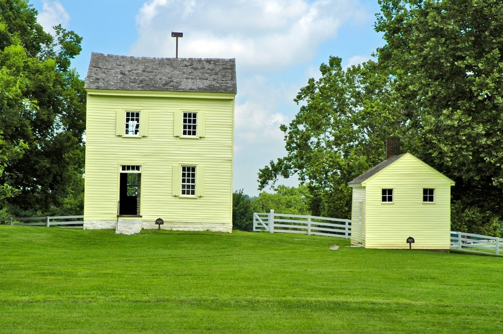 A simple two story, yellow family Home on the grounds of a Shaker Village in Kentucky.