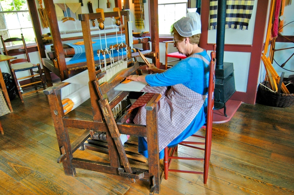A woman is making cloth from spun wool at Pleasant Hill, a Shaker Village in Kentucky.