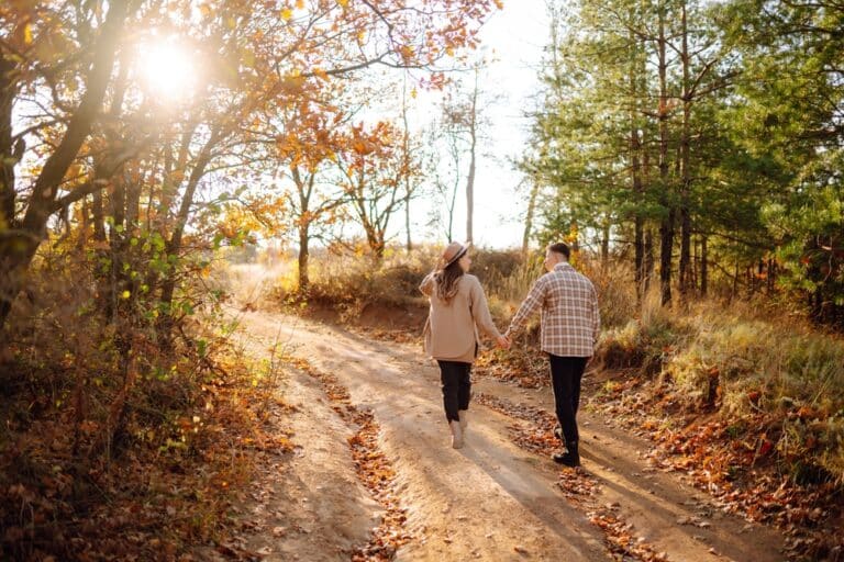 Couple walks hand-in-hand down country road during fall in Kentucky during their stay at our Bed and Breakfast in KY.